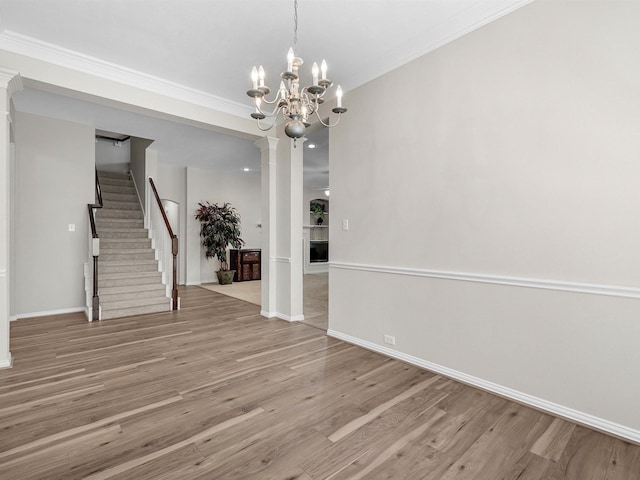 14402 Cottage Timbers Ln, Houston, TX 77044 - spare room with a chandelier, crown molding, wood finished floors, decorative columns, and stairs