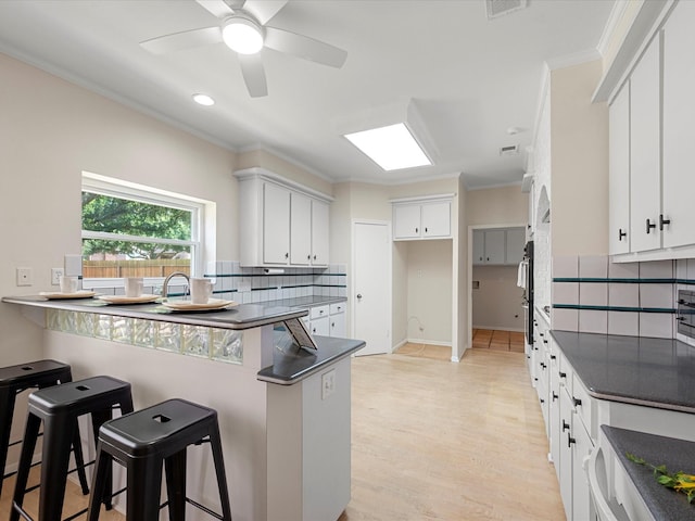 1735 Hodge Lake Ln, Sugar Land, TX 77478 - kitchen with a peninsula, dark countertops, crown molding, backsplash, and a breakfast bar