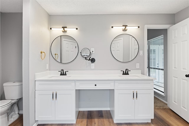 2314 Peaceful Valley Dr, Spring, TX 77373 - full bathroom featuring toilet, double vanity, wood finished floors, and a textured ceiling