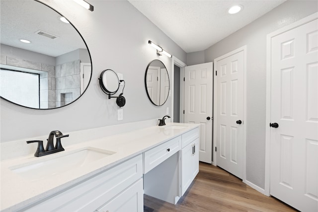 2314 Peaceful Valley Dr, Spring, TX 77373 - bathroom with double vanity, wood finished floors, recessed lighting, baseboards, and a textured ceiling