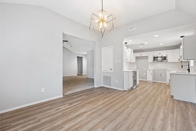 2314 Peaceful Valley Dr, Spring, TX 77373 - unfurnished living room featuring a sink, a chandelier, light wood-style floors, vaulted ceiling, and baseboards