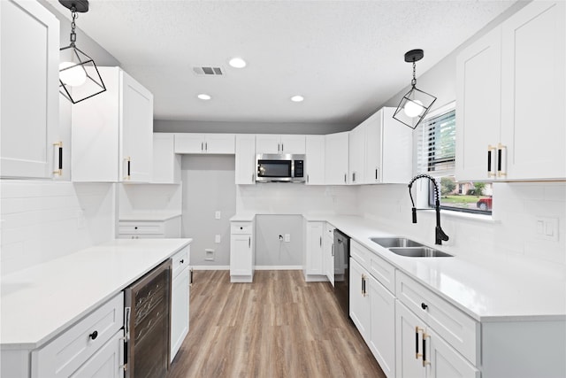 2314 Peaceful Valley Dr, Spring, TX 77373 - kitchen featuring stainless steel microwave, beverage cooler, a sink, light wood-type flooring, and black dishwasher