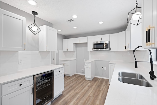 2314 Peaceful Valley Dr, Spring, TX 77373 - kitchen featuring wine cooler, stainless steel microwave, a sink, light wood-style floors, and tasteful backsplash