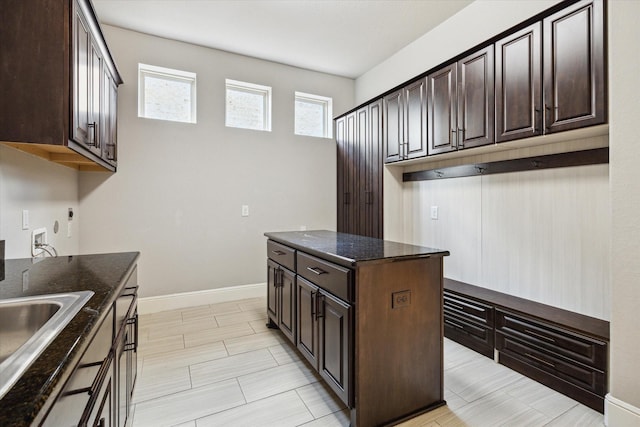 10306 Grape Creek Grove Ln, Cypress, TX 77433 - kitchen featuring dark brown cabinets, dark stone counters, a sink, baseboards, and a center island