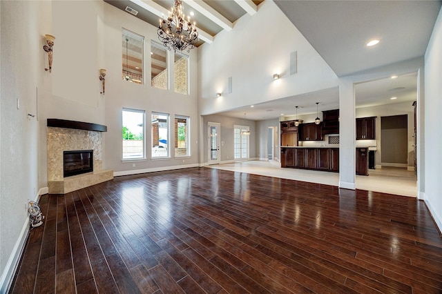 10306 Grape Creek Grove Ln, Cypress, TX 77433 - unfurnished living room featuring baseboards, a premium fireplace, a chandelier, wood finished floors, and beamed ceiling