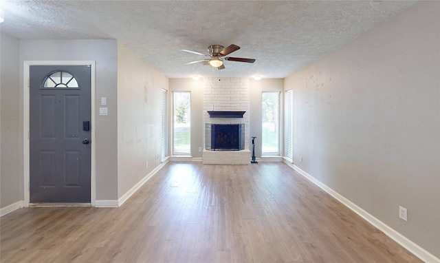 3907 Texas Ave, Dickinson, TX 77539 - unfurnished living room featuring ceiling fan, wood finished floors, a fireplace, a textured ceiling, and baseboards