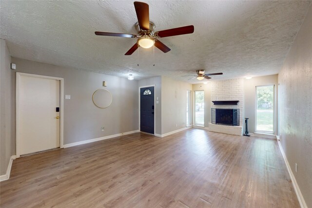 3907 Texas Ave, Dickinson, TX 77539 - unfurnished living room with light wood-style flooring, a ceiling fan, a textured ceiling, a fireplace, and baseboards