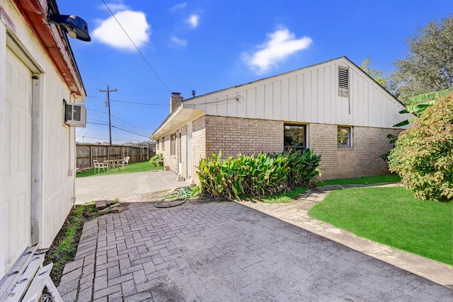 8007 Twin Hills Dr, Houston, TX 77071 - view of side of home featuring brick siding, a patio, board and batten siding, and a chimney