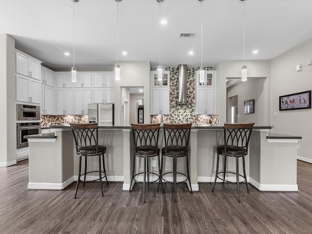 3466 Oakheath Manor Way, Houston, TX 77365 - kitchen with stainless steel appliances, wall chimney exhaust hood, backsplash, white cabinets, and recessed lighting