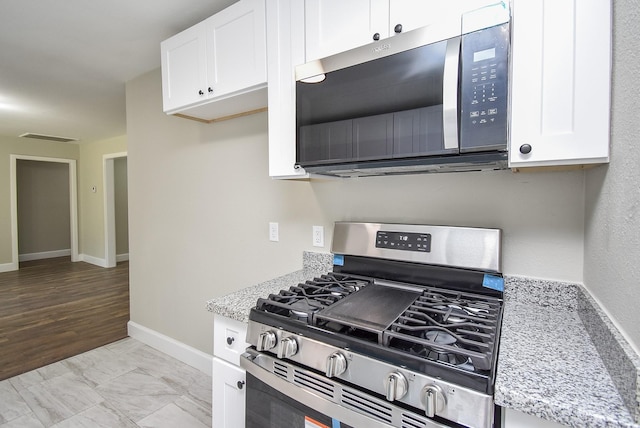 5906 Melanite Ave, Houston, TX 77053 - kitchen featuring appliances with stainless steel finishes, white cabinetry, light stone counters, and baseboards