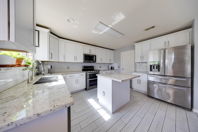 8106 Sweetstone Bluff Ln, Cypress, TX 77433 - kitchen with stainless steel appliances, a sink, tasteful backsplash, a kitchen island, and white cabinets