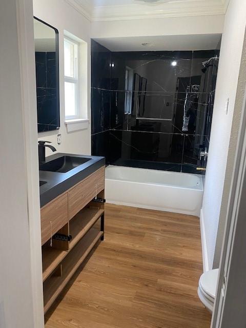 8107 S Braeswood Blvd, Houston, TX 77071 - bathroom with ornamental molding, toilet, vanity, washtub / shower combination, and wood finished floors