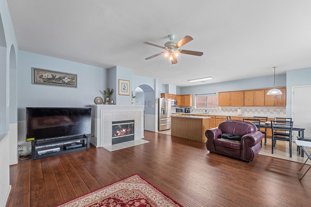 16310 Autumn Leigh Dr, Houston, TX 77083 - living room with arched walkways, hardwood / wood-style flooring, ceiling fan, and a tile fireplace