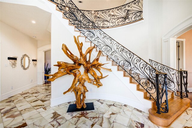 5302 Val Verde St, Houston, TX 77056 - staircase featuring arched walkways, a high ceiling, baseboards, marble finish flooring, and recessed lighting