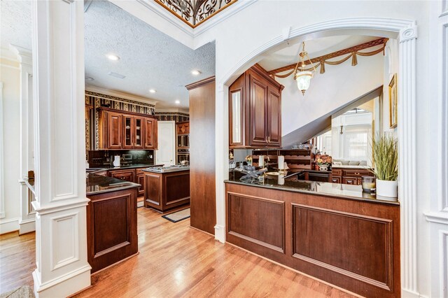 5302 Val Verde St, Houston, TX 77056 - kitchen with crown molding, a chandelier, light wood finished floors, dark countertops, and glass insert cabinets
