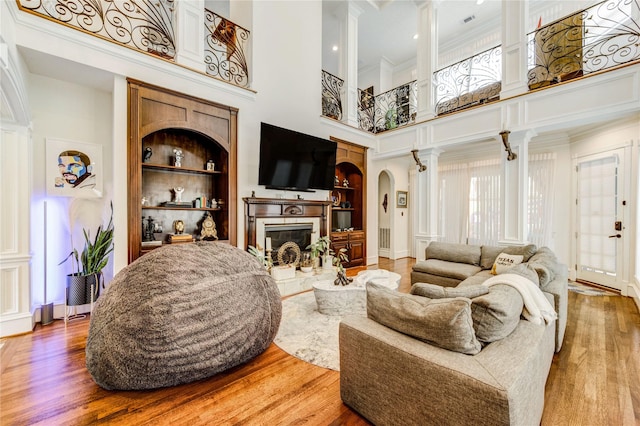 5302 Val Verde St, Houston, TX 77056 - living area featuring a high ceiling, a glass covered fireplace, wood finished floors, built in features, and arched walkways