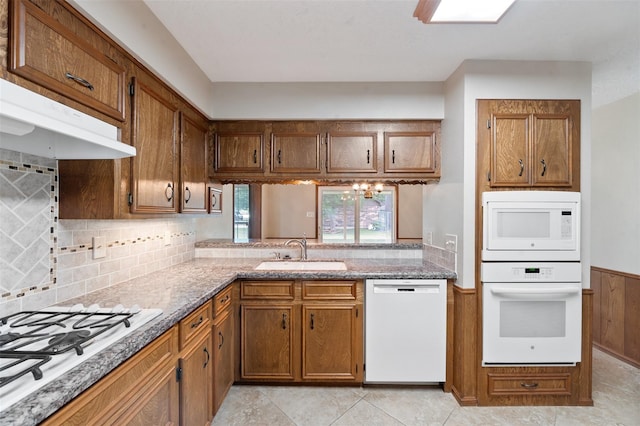 534 W Hufsmith Rd, Tomball, TX 77375 - kitchen featuring white appliances, a sink, brown cabinetry, backsplash, and under cabinet range hood