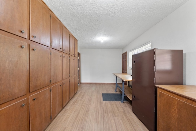 534 W Hufsmith Rd, Tomball, TX 77375 - kitchen featuring light wood-type flooring, a textured ceiling, brown cabinetry, light countertops, and baseboards