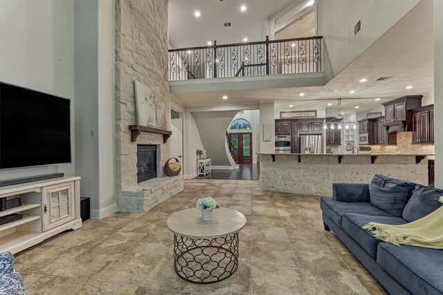 21603 Fairhaven Creek Dr, Cypress, TX 77433 - living area featuring a towering ceiling, a fireplace, baseboards, recessed lighting, and light stone finish flooring