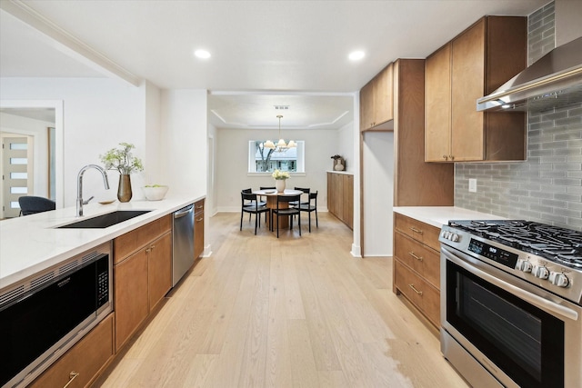 4411 Colchester St, Houston, TX 77018 - kitchen with appliances with stainless steel finishes, a sink, wall chimney exhaust hood, light wood-style floors, and tasteful backsplash