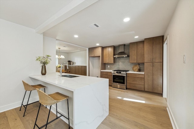 4411 Colchester St, Houston, TX 77018 - kitchen featuring stainless steel gas range, a sink, wall chimney range hood, a kitchen bar, and tasteful backsplash