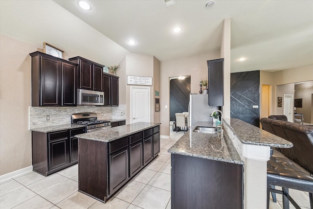 4914 Mountain Maple Trl, Rosenberg, TX 77471 - kitchen with appliances with stainless steel finishes, a sink, decorative backsplash, light stone counters, and a kitchen bar
