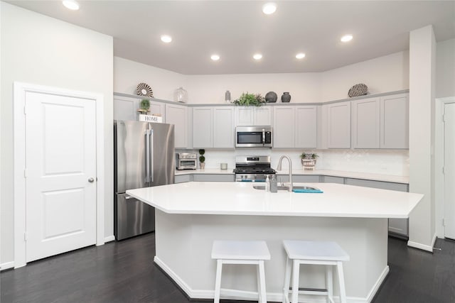 7334 Lake Arrowhead Ln, Porter, TX 77365 - kitchen with appliances with stainless steel finishes, a sink, dark wood-type flooring, a kitchen island with sink, and light countertops