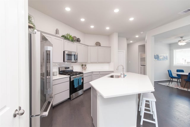 7334 Lake Arrowhead Ln, Porter, TX 77365 - kitchen with appliances with stainless steel finishes, a sink, dark wood-style floors, an island with sink, and light countertops
