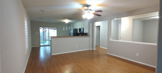 2518 Skyview Cove Ct, Houston, TX 77047 - kitchen with stainless steel microwave, wood finished floors, ceiling fan, white cabinetry, and baseboards