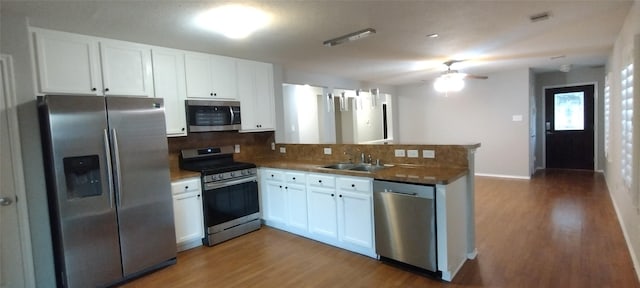 2518 Skyview Cove Ct, Houston, TX 77047 - kitchen featuring stainless steel appliances, a sink, a peninsula, decorative backsplash, and wood finished floors