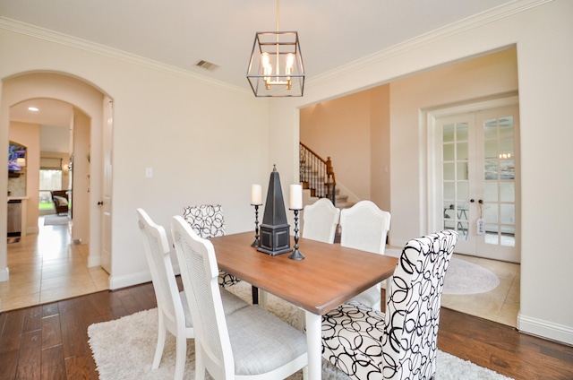 4511 Wickby St, Fulshear, TX 77441 - dining room featuring french doors, arched walkways, wood-type flooring, a chandelier, and crown molding