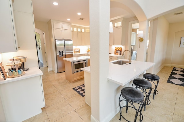 4511 Wickby St, Fulshear, TX 77441 - kitchen with appliances with stainless steel finishes, a kitchen island with sink, arched walkways, a breakfast bar area, and recessed lighting