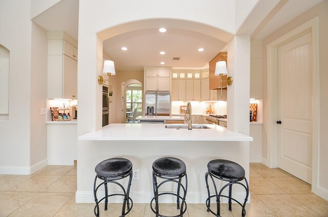 4511 Wickby St, Fulshear, TX 77441 - kitchen featuring arched walkways, stainless steel refrigerator with ice dispenser, a center island with sink, a kitchen bar, and recessed lighting