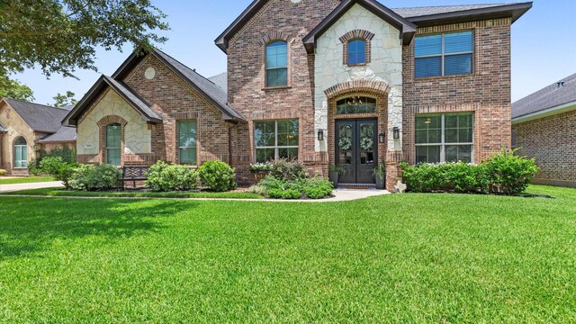 4511 Wickby St, Fulshear, TX 77441 - french country style house featuring french doors, brick siding, a front lawn, and stone siding
