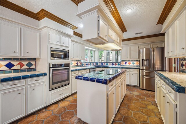 5718 Glenmere Ln, Spring, TX 77379 - kitchen with stainless steel appliances, crown molding, a textured ceiling, tile counters, and tasteful backsplash