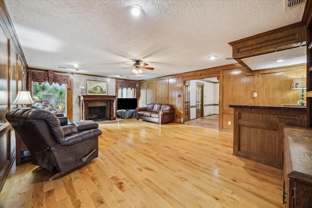 5718 Glenmere Ln, Spring, TX 77379 - living area featuring a textured ceiling, a ceiling fan, crown molding, light wood-style flooring, and a fireplace