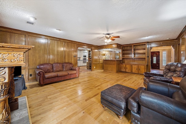 5718 Glenmere Ln, Spring, TX 77379 - living room with wooden walls, ceiling fan, light wood-type flooring, and a textured ceiling
