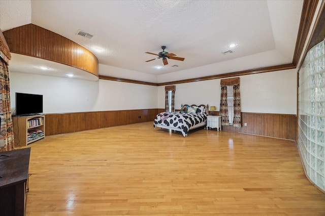 5718 Glenmere Ln, Spring, TX 77379 - bedroom featuring a wainscoted wall, light wood-style floors, wooden walls, a textured ceiling, and a ceiling fan
