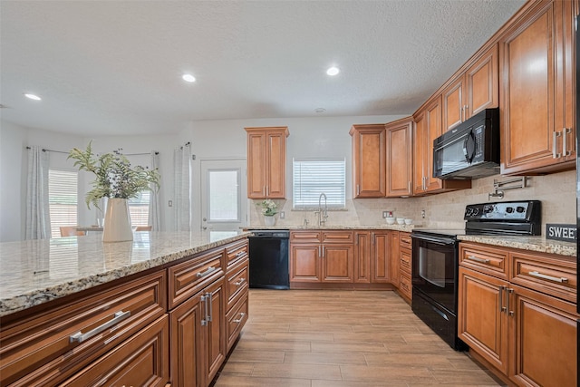 5722 Henniker Dr, Houston, TX 77041 - kitchen with black appliances, light stone countertops, light wood-style floors, brown cabinets, and tasteful backsplash
