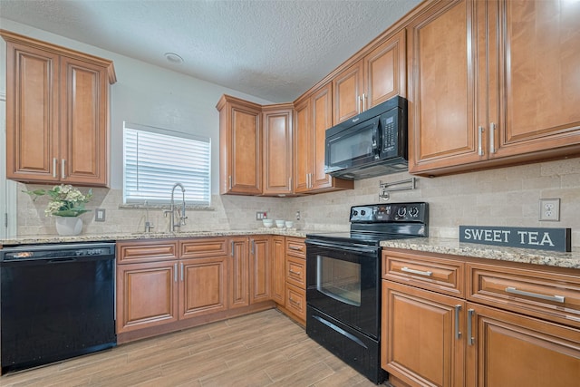 5722 Henniker Dr, Houston, TX 77041 - kitchen with black appliances, a sink, brown cabinetry, light wood-type flooring, and light stone counters