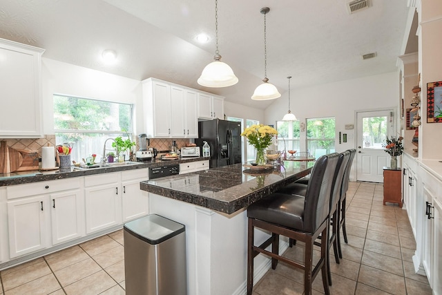2 Camborn Pl, The Woodlands, TX 77384 - kitchen with black fridge, lofted ceiling, tasteful backsplash, light tile patterned flooring, and white cabinetry