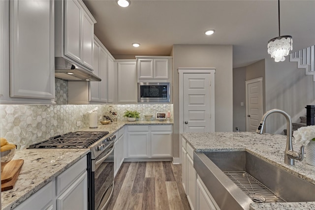 127 Kingsley Grove St, Montgomery, TX 77316 - kitchen with appliances with stainless steel finishes, a sink, light wood-style floors, white cabinets, and backsplash