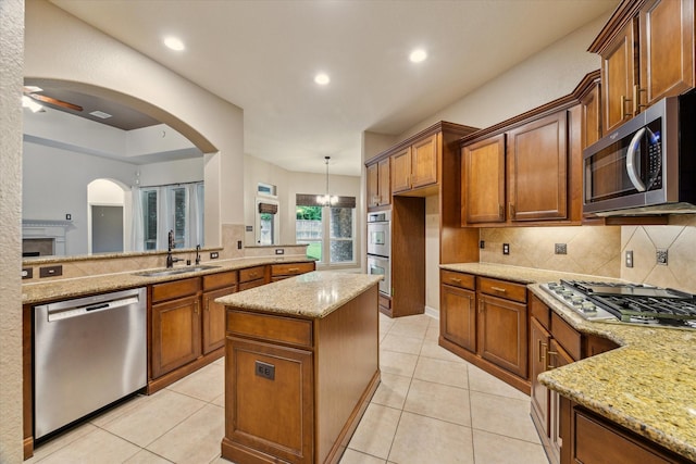 28314 Shining Creek Ln, Spring, TX 77386 - kitchen with appliances with stainless steel finishes, a sink, light stone counters, tasteful backsplash, and brown cabinetry