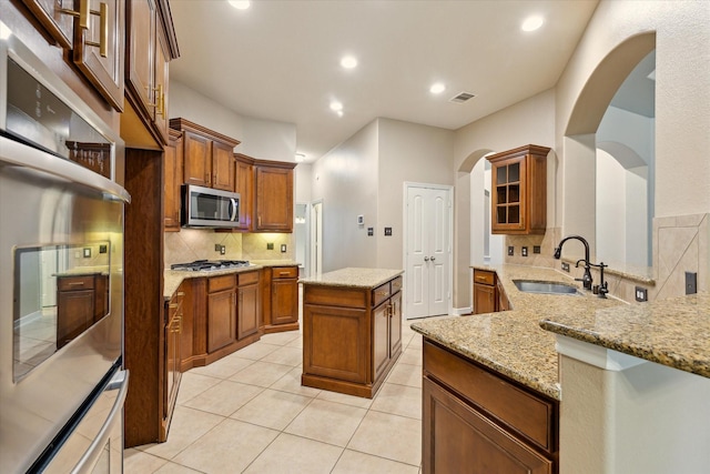 28314 Shining Creek Ln, Spring, TX 77386 - kitchen featuring appliances with stainless steel finishes, a sink, a center island, decorative backsplash, and brown cabinets