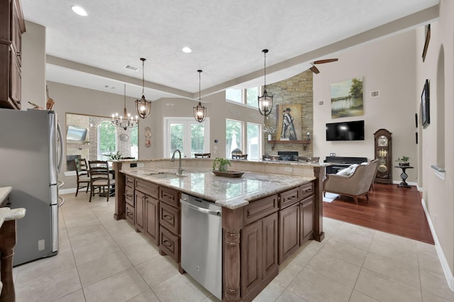 11415 W Kristina Cir, Montgomery, TX 77316 - kitchen featuring appliances with stainless steel finishes, a sink, a fireplace, light tile patterned flooring, and a large island with sink
