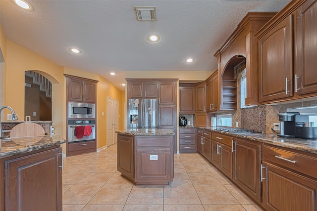 7207 Alder Springs Ct, Katy, TX 77494 - kitchen featuring stainless steel appliances, arched walkways, backsplash, dark stone counters, and a kitchen island
