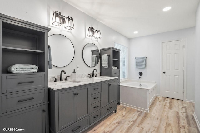 647 Cypresswood Trce, Spring, TX 77373 - bathroom featuring double vanity, a garden tub, wood finished floors, and recessed lighting