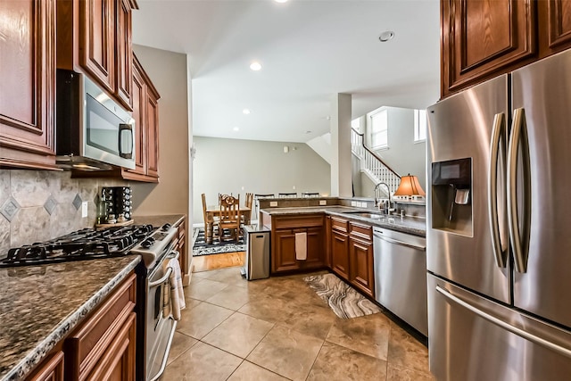 1513 Nagle St, Houston, TX 77003 - kitchen featuring appliances with stainless steel finishes, tasteful backsplash, a peninsula, dark stone counters, and light tile patterned flooring
