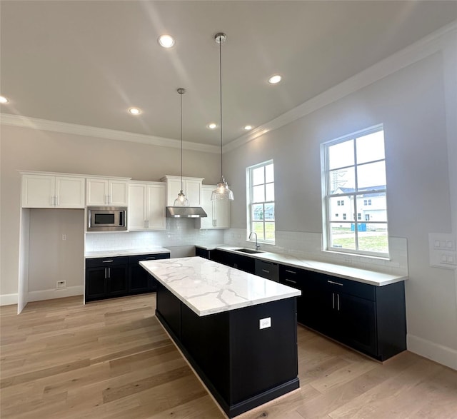 2620 Lake Kolbe Ln, Houston, TX 77080 - kitchen with stainless steel microwave, dark cabinetry, ornamental molding, under cabinet range hood, and decorative backsplash