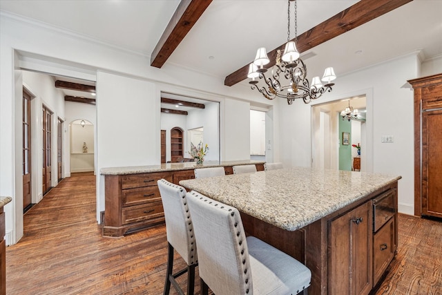 5418 Braeburn Dr, Bellaire, TX 77401 - kitchen featuring a chandelier, dark wood-type flooring, light stone counters, beamed ceiling, and a kitchen island